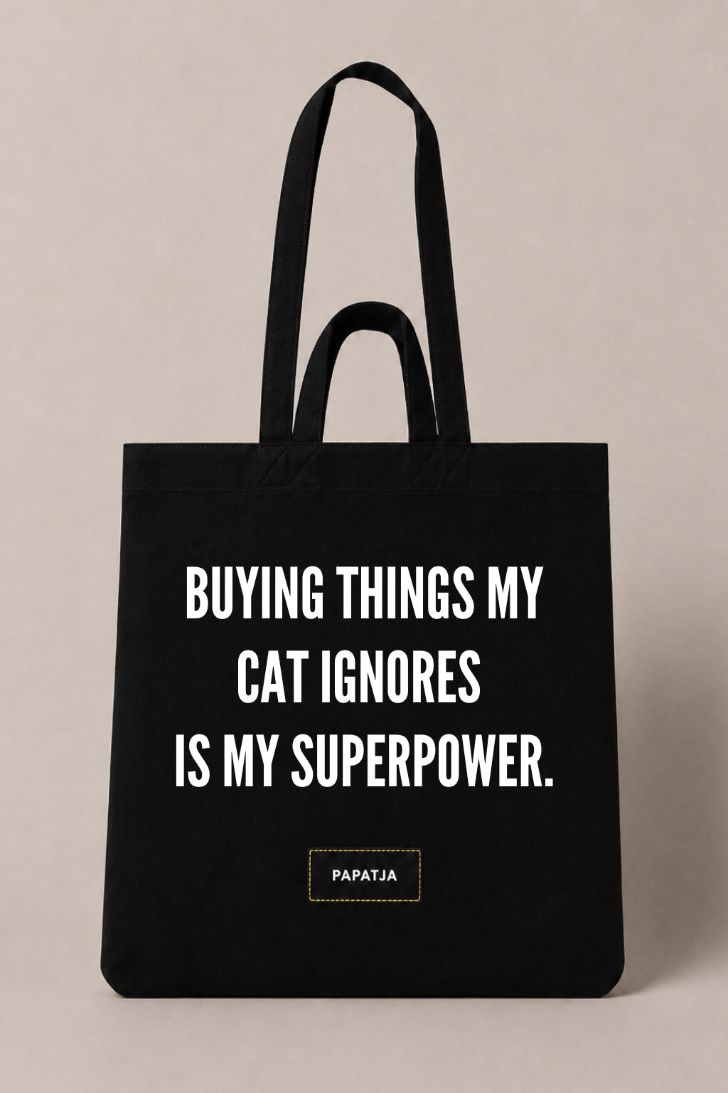 Black cotton PAPATJA tote bag with the quote Buying Things My Cat Ignores Is My Superpower, a funny gift for cat lovers.