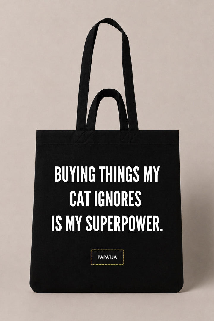 Black cotton PAPATJA tote bag with the quote Buying Things My Cat Ignores Is My Superpower, a funny gift for cat lovers.