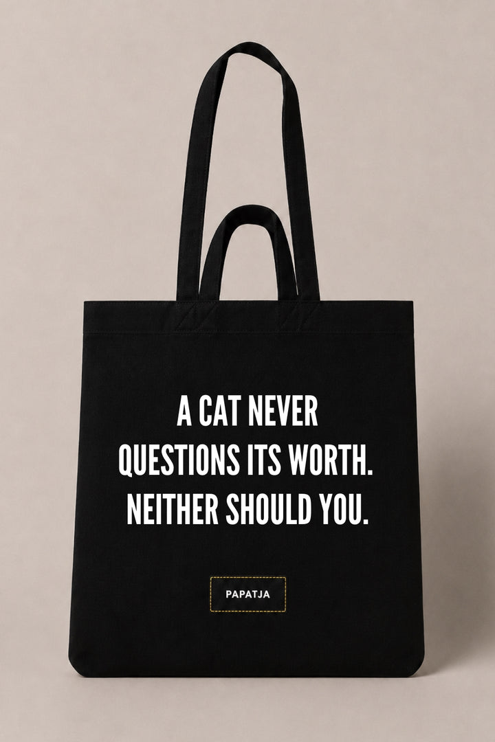 Black cotton PAPATJA tote bag with the quote A Cat Never Questions Its Worth. Neither Should You, a thoughtful gift for cat lovers.