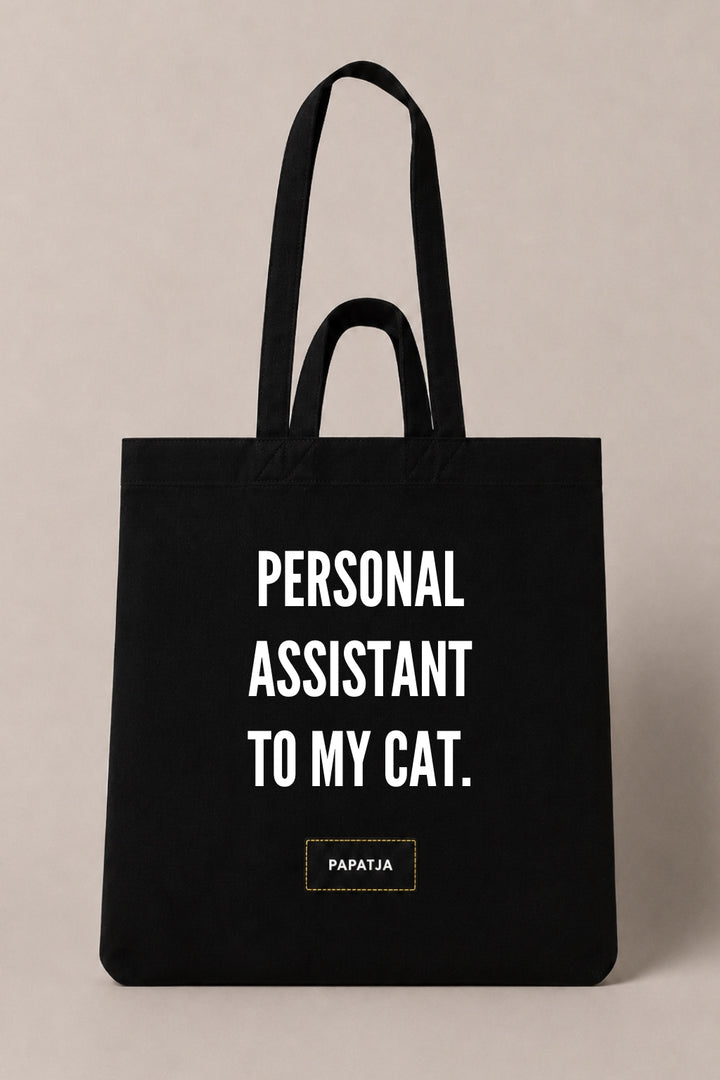 Black cotton PAPATJA tote bag with the quote Personal Assistant to My Cat, a funny gift for cat lovers.
