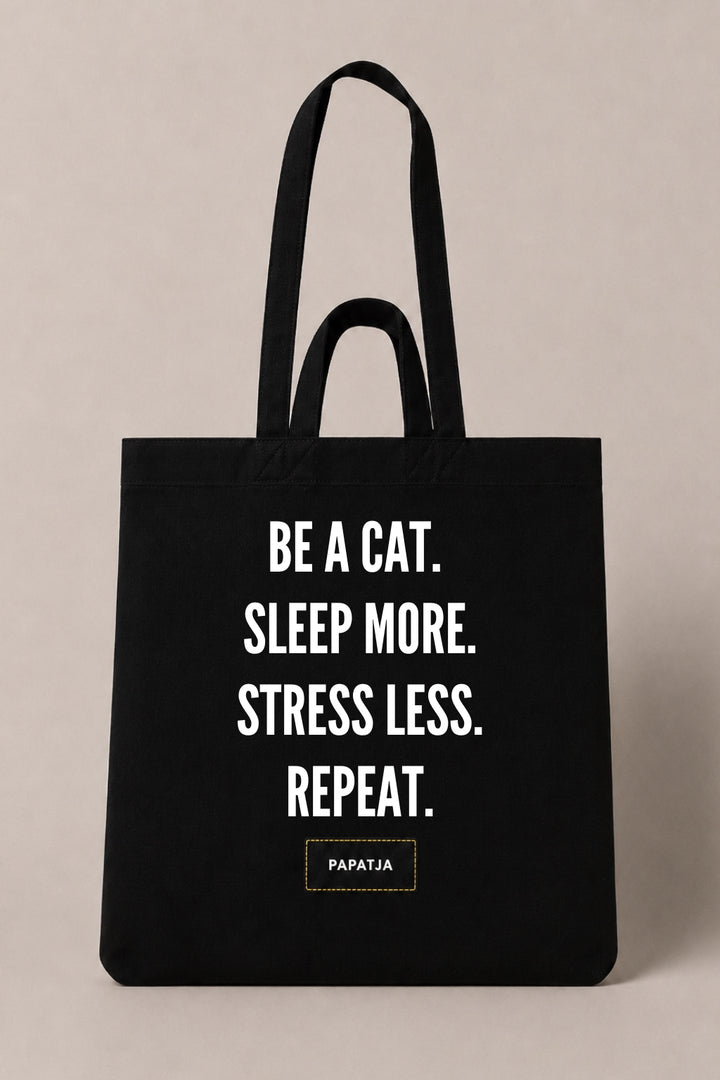 Black cotton PAPATJA tote bag with the quote Be a Cat. Sleep More. Stress Less. Repeat., a thoughtful gift for cat lovers.