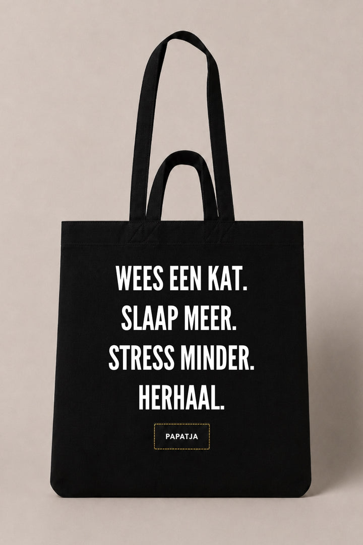 Zwarte katoenen PAPATJA tas met de tekst Wees een kat. Slaap meer. Stress minder. Herhaal., leuk cadeau voor kattenliefhebbers die houden van rust en kattenwijsheid.